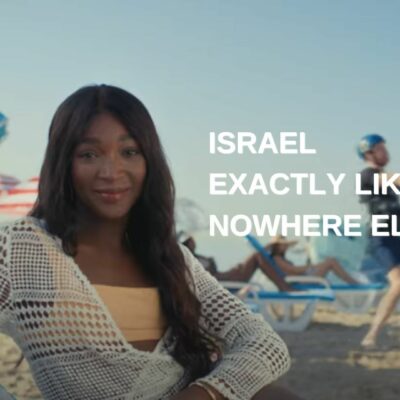 אשה יושבת בים ויש כיתוב שמעודד ביקור בישראל. קמפיין של משרד התיירות בישראל