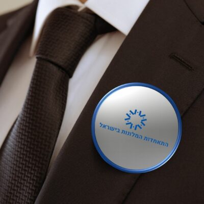 תקריב של איש בחליפה הלובש סיכת כפתור שרשום בה התאחדות המלונות