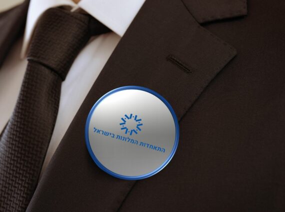 תקריב של איש בחליפה הלובש סיכת כפתור שרשום בה התאחדות המלונות