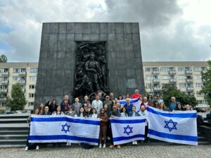 משלחת של מלונאים למסע בפולין אוחזים דגלי ישראל